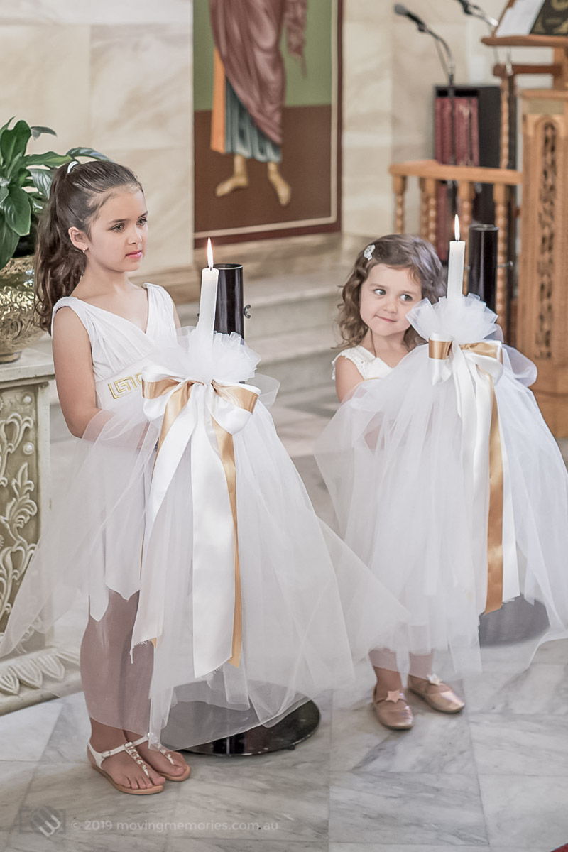 young sisters at the altar hold the candles, known as Lambada, used in a Greek Orthodox Christening in Sydney