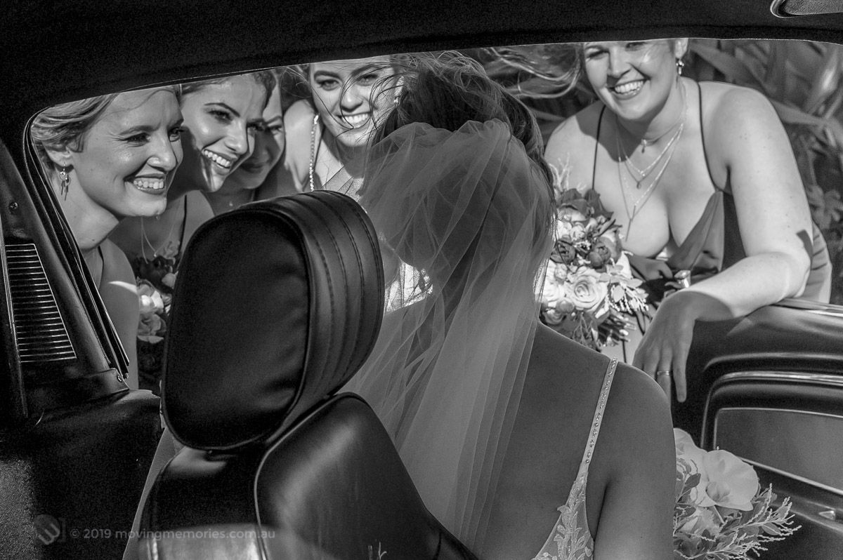 Sydney Bride Rachel arriving at her wedding ceremony. Greeted by her bride's maids as the bride is about to step out of the bridal Ford Mustang at the Lakes Sydney