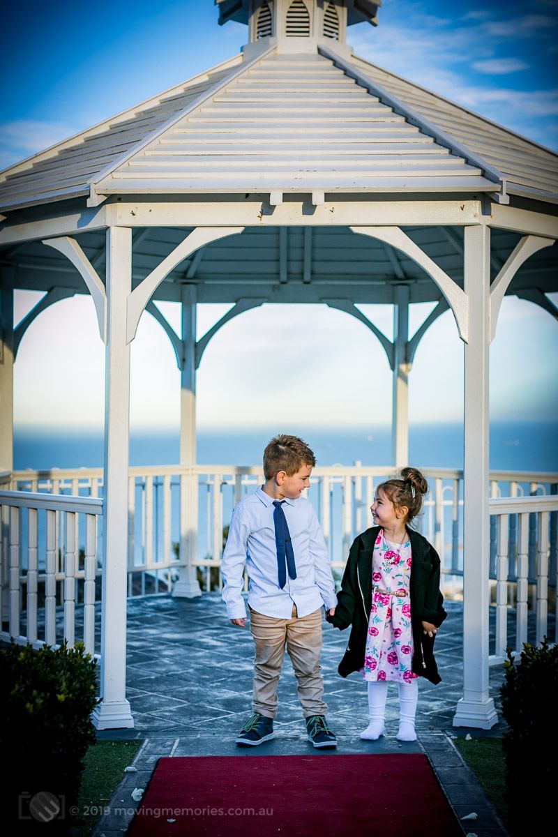 the-big-brothe-and-sister-hold-hands-in-the-garden-gazebo-before-the-guests-arrive-at-the-reception-for-Baby-Girl-Andrea-Christening-at-Panorama-House-Bulli-Tops-near-Wollongong